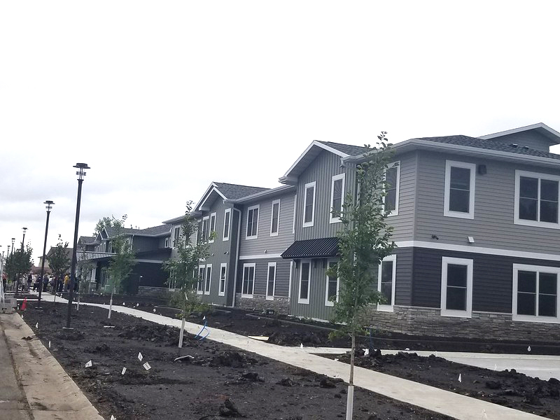 a gray apartment building with newly planted trees